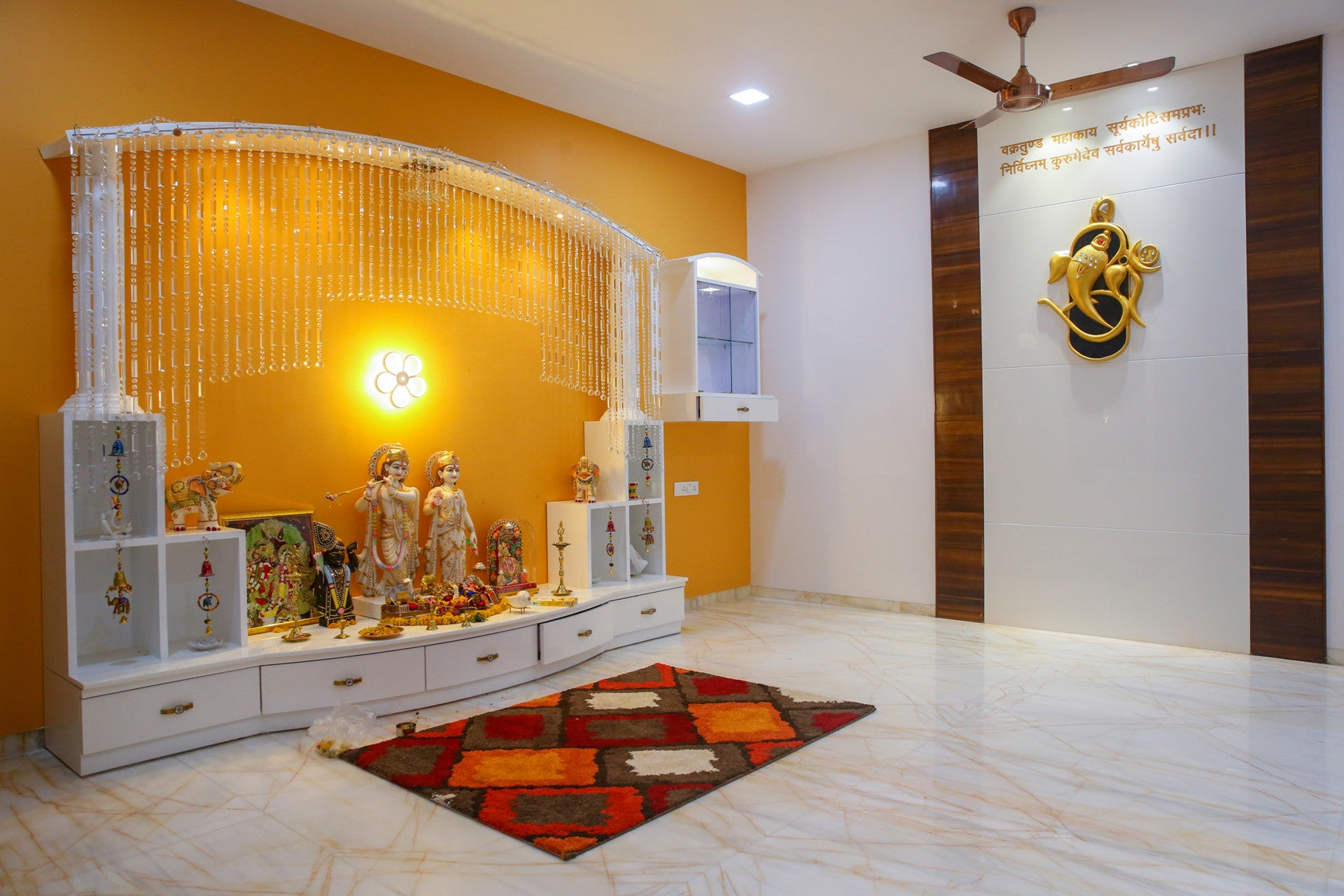 Wooden mandir with carved doors and brass bells in a Pooja room designed by Bamoo Interio